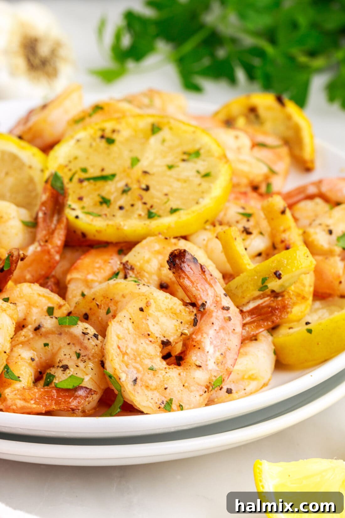 Crispy Air Fryer Shrimp 2 A plate of perfectly cooked, golden air fryer shrimp garnished with fresh parsley and lemon wedges.
