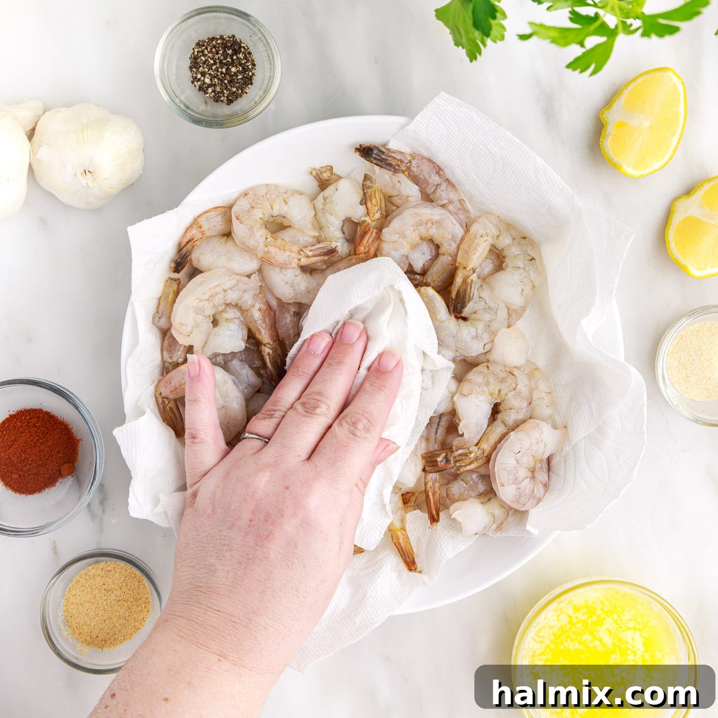 Crispy Air Fryer Shrimp 5 Patting raw shrimp dry with a paper towel on a cutting board.