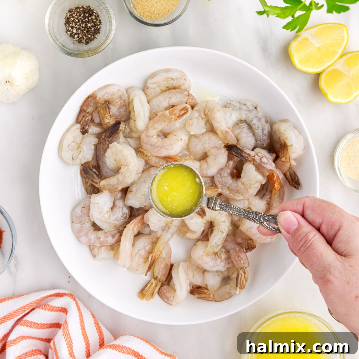 Crispy Air Fryer Shrimp 6 Pouring melted butter over raw shrimp in a mixing bowl.
