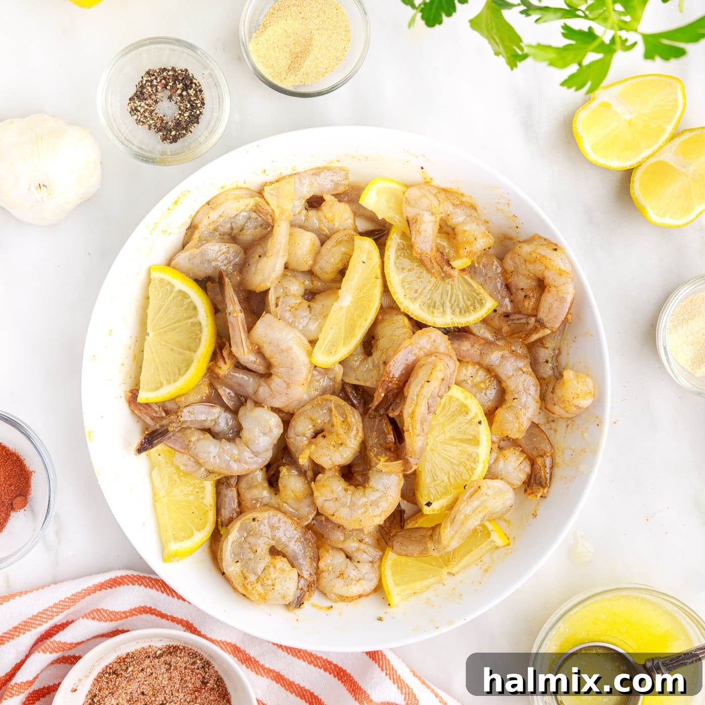 Crispy Air Fryer Shrimp 9 Lemon wedges mixed with raw seasoned shrimp in a mixing bowl.