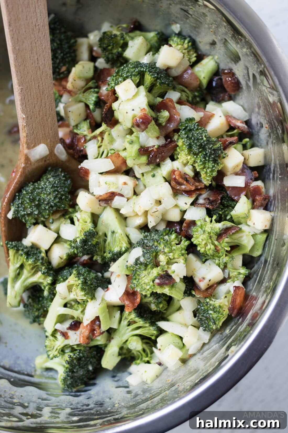 Creamy Broccoli Salad 2 A vibrant bowl of classic broccoli salad, featuring fresh green broccoli florets, crispy bacon bits, shredded cheese, and diced red onion, tossed in a creamy dressing.