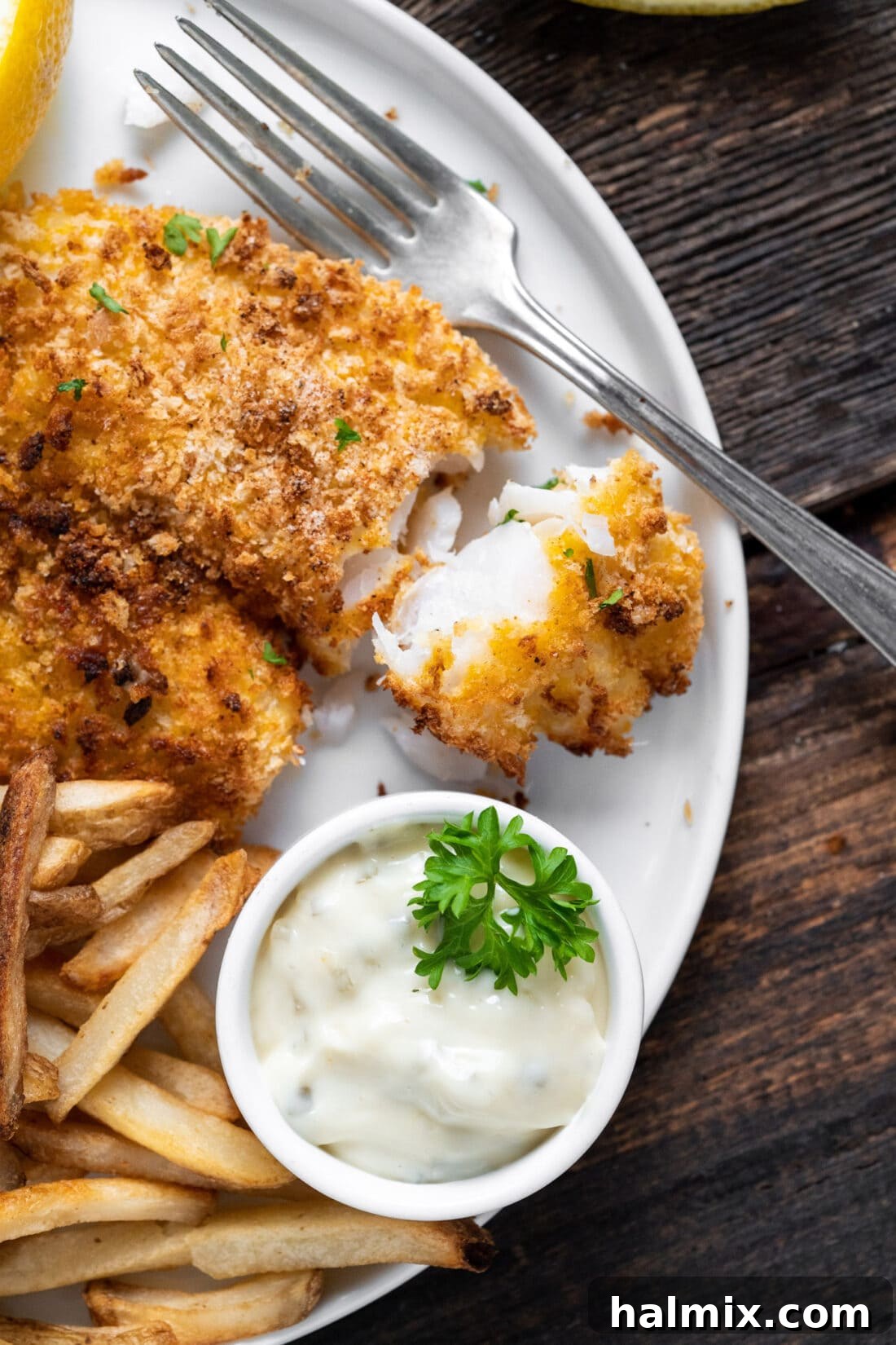 Air Fryer Fish on a plate with a lemon wedge and parsley