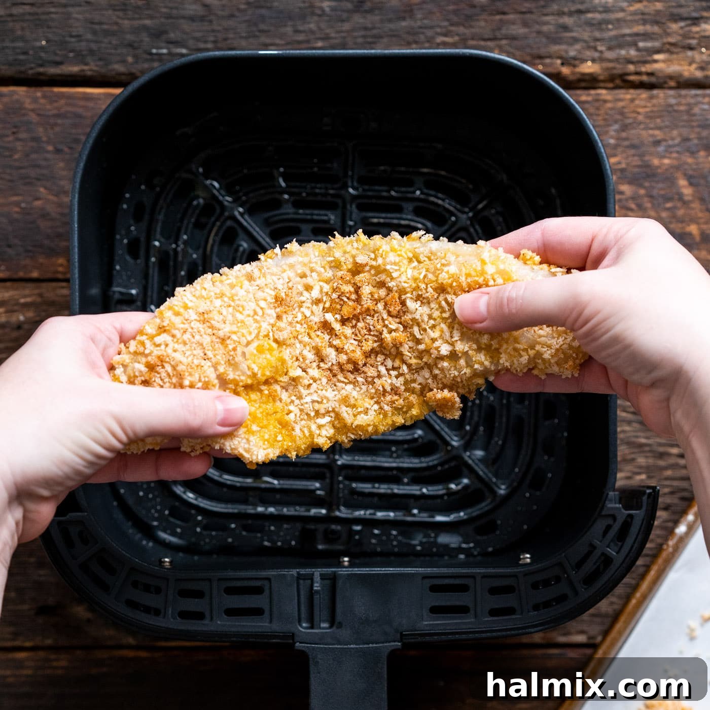 Breaded fish fillets positioned above the air fryer basket, ready to be cooked