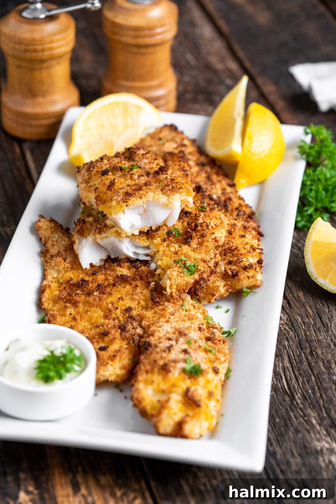 A large platter of golden-brown Air Fryer Fish fillets, garnished with fresh parsley and lemon