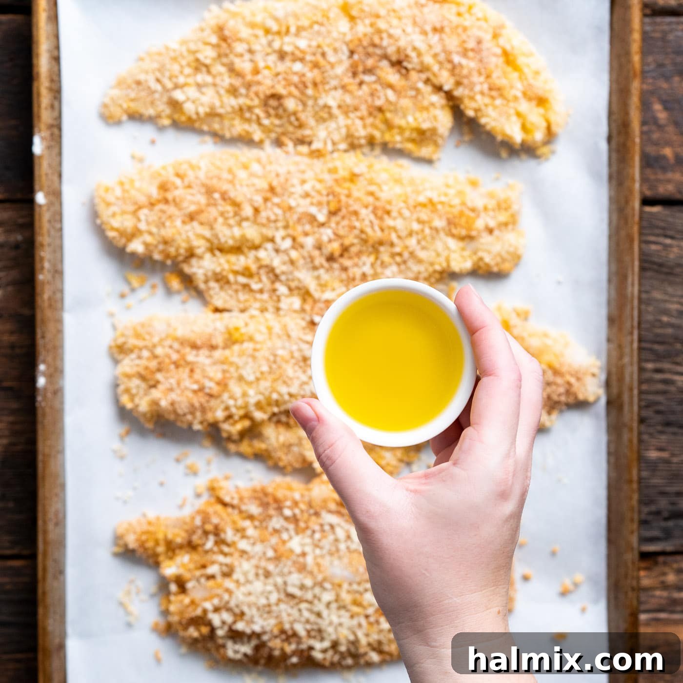 Drizzling olive oil over the breaded fish fillets before air frying