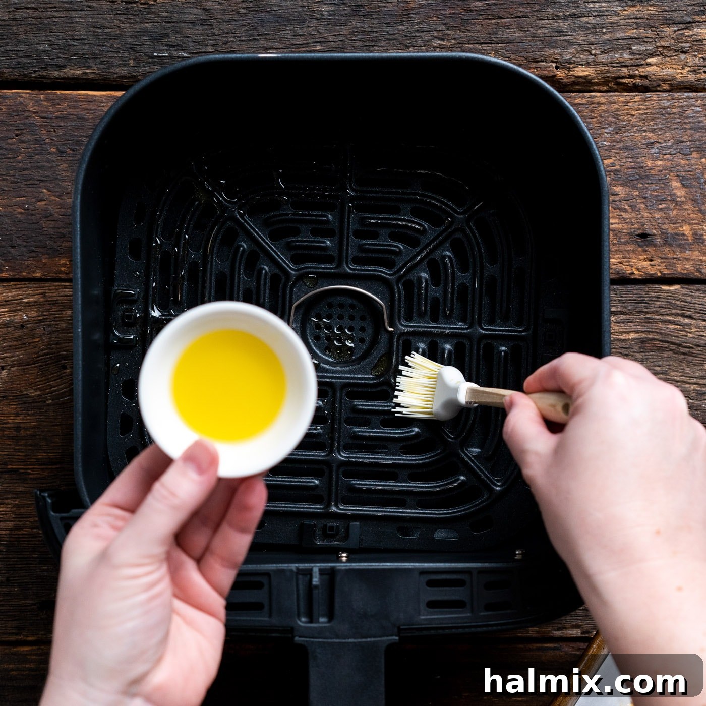 Brushing the air fryer basket with olive oil to prevent sticking