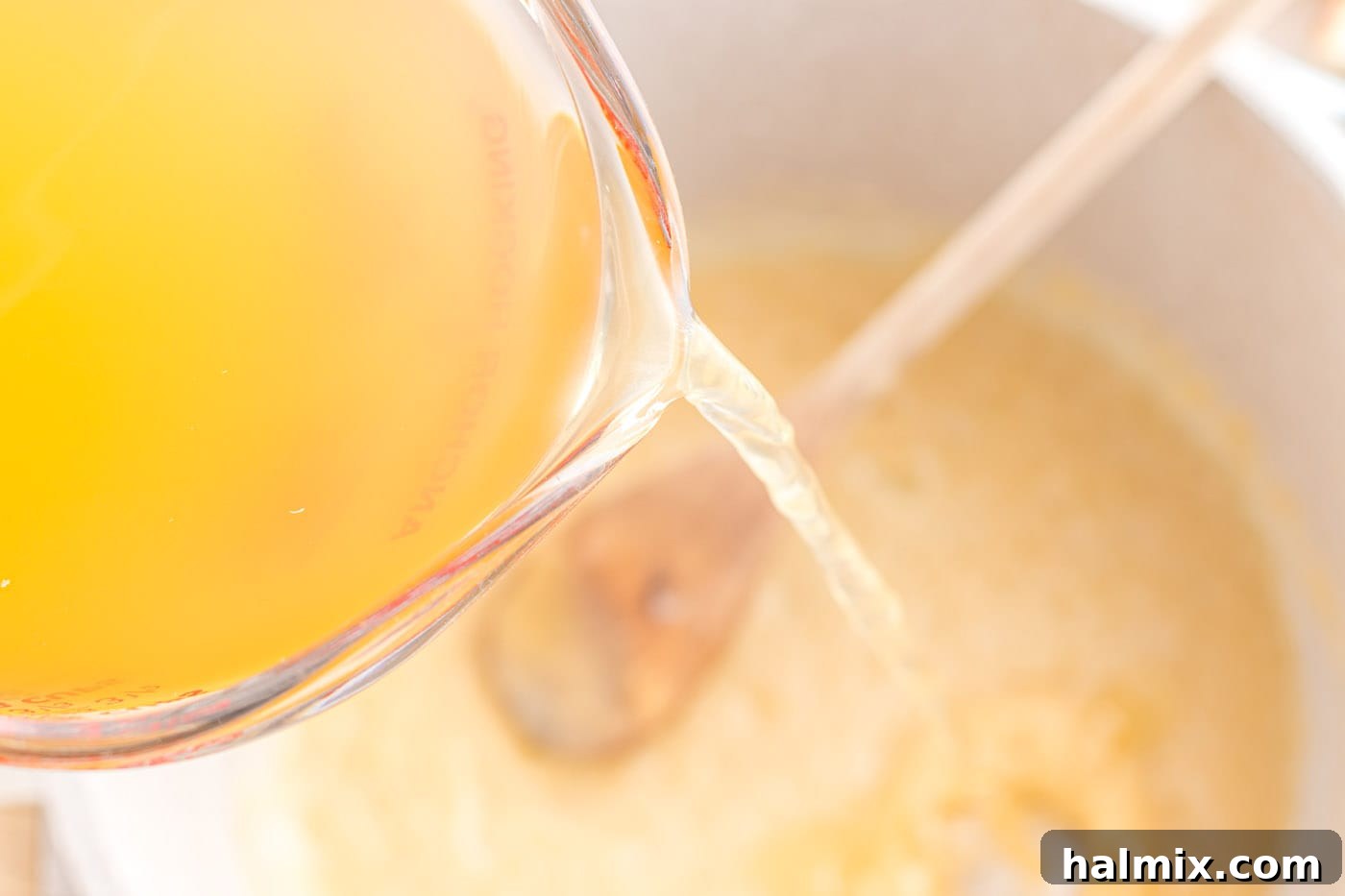 Creamy Chicken Noodle Delight 7 Chicken stock being poured gradually into a pot with a roux.