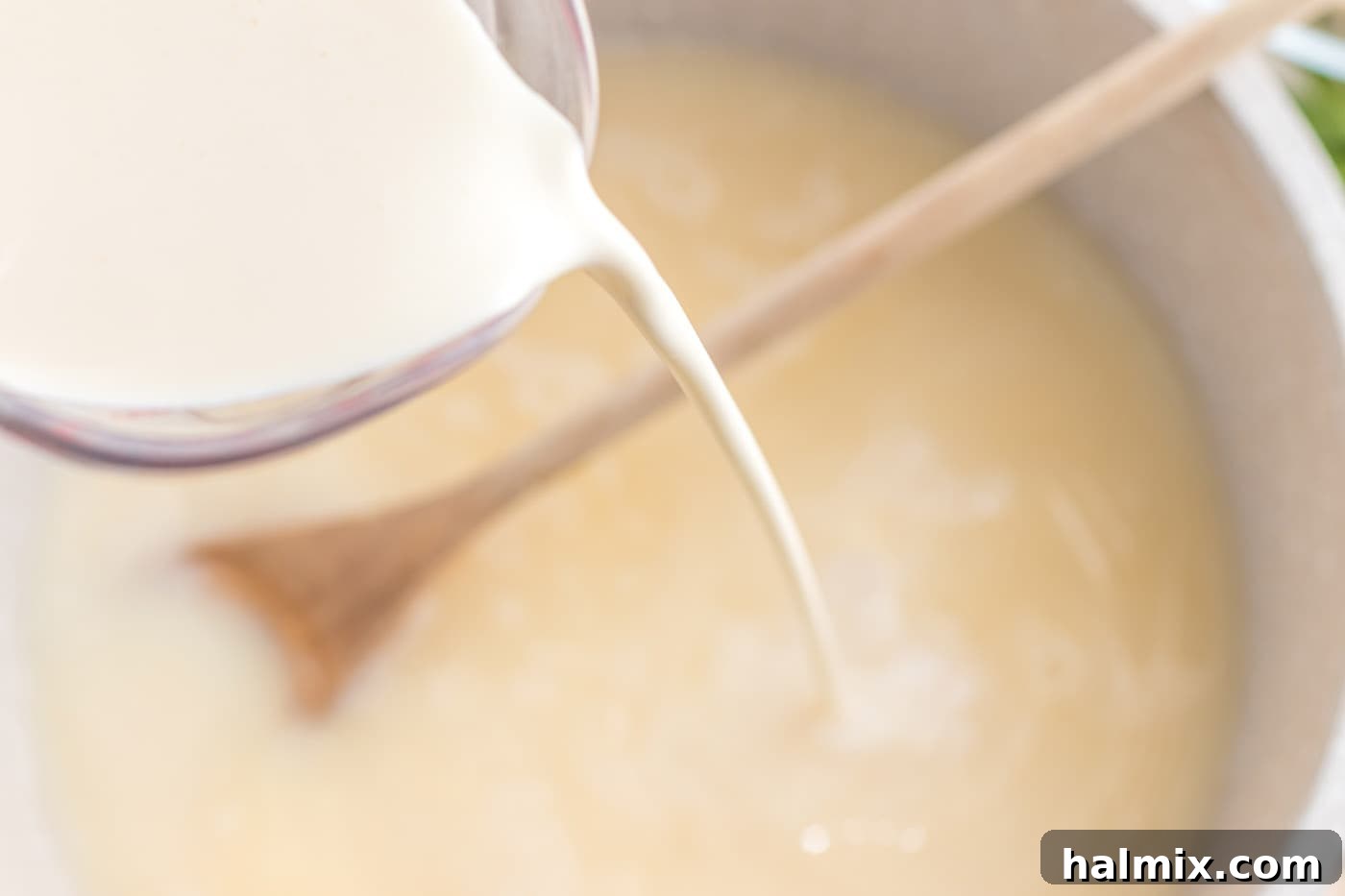 Creamy Chicken Noodle Delight 8 Heavy cream being poured into the sauce mixture in a pot.