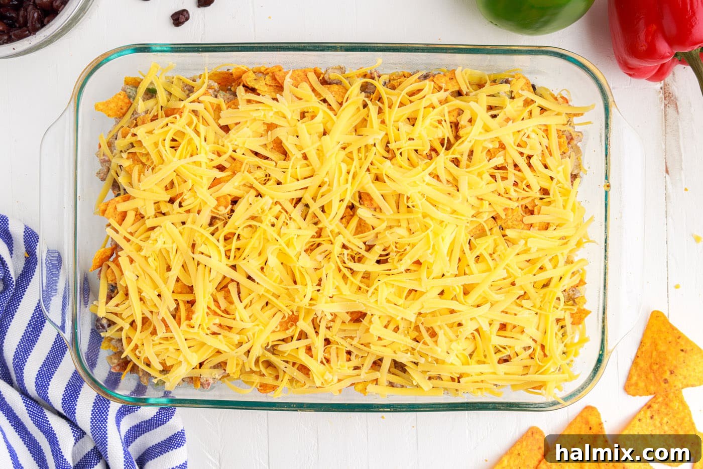 The top layer of shredded cheese generously applied over the Dorito casserole.