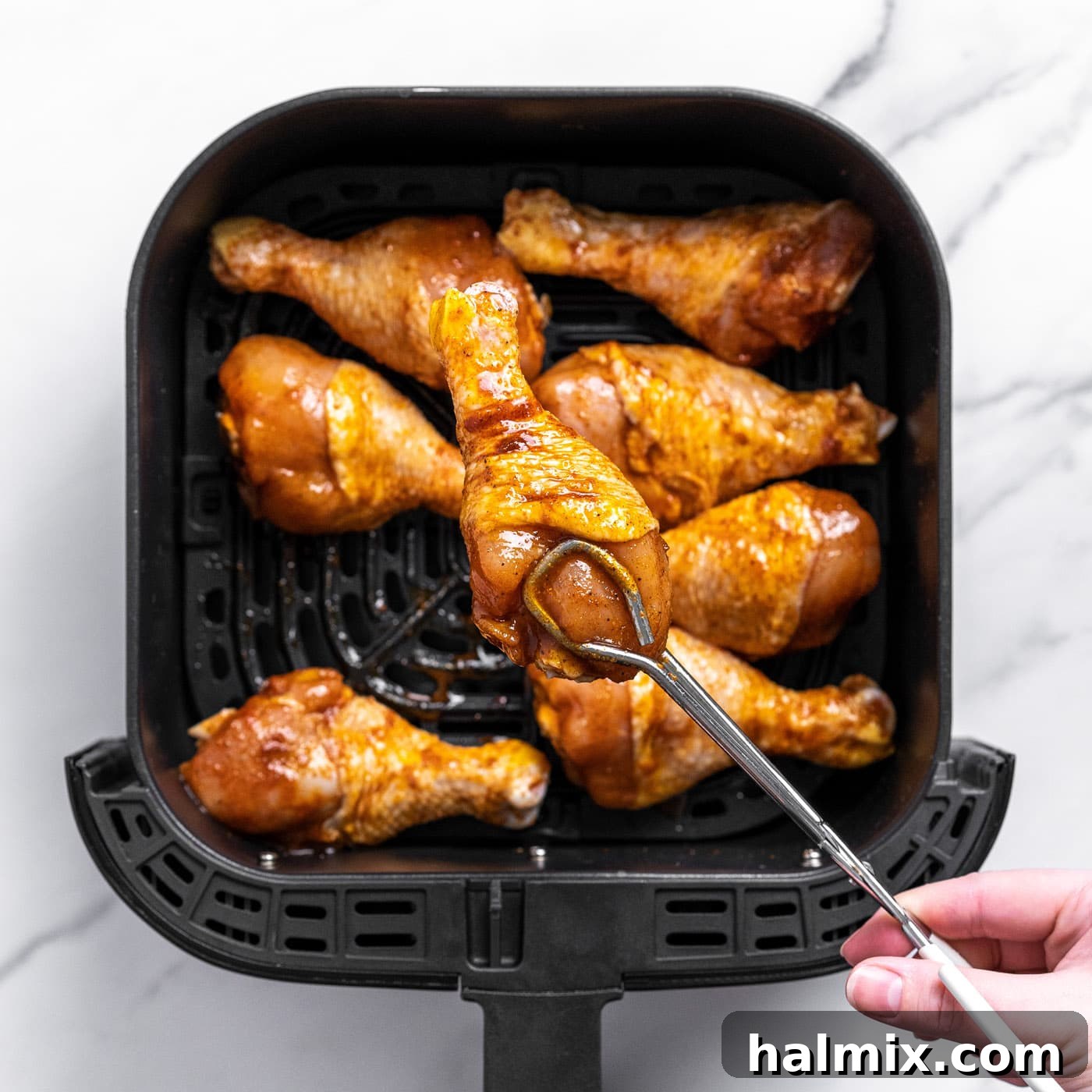 Golden Air Fried Drumsticks 6 tongs placing chicken leg into air fryer
