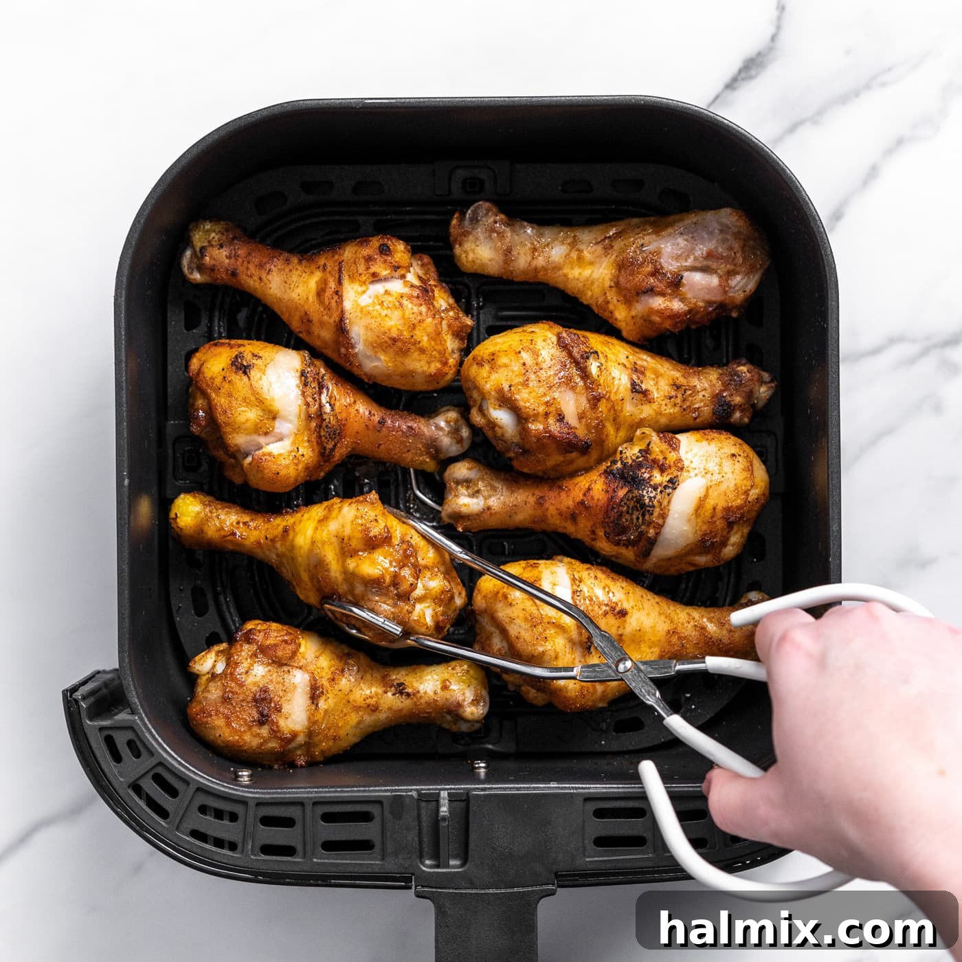 Golden Air Fried Drumsticks 7 grabbing chicken drumstick in air fryer basket