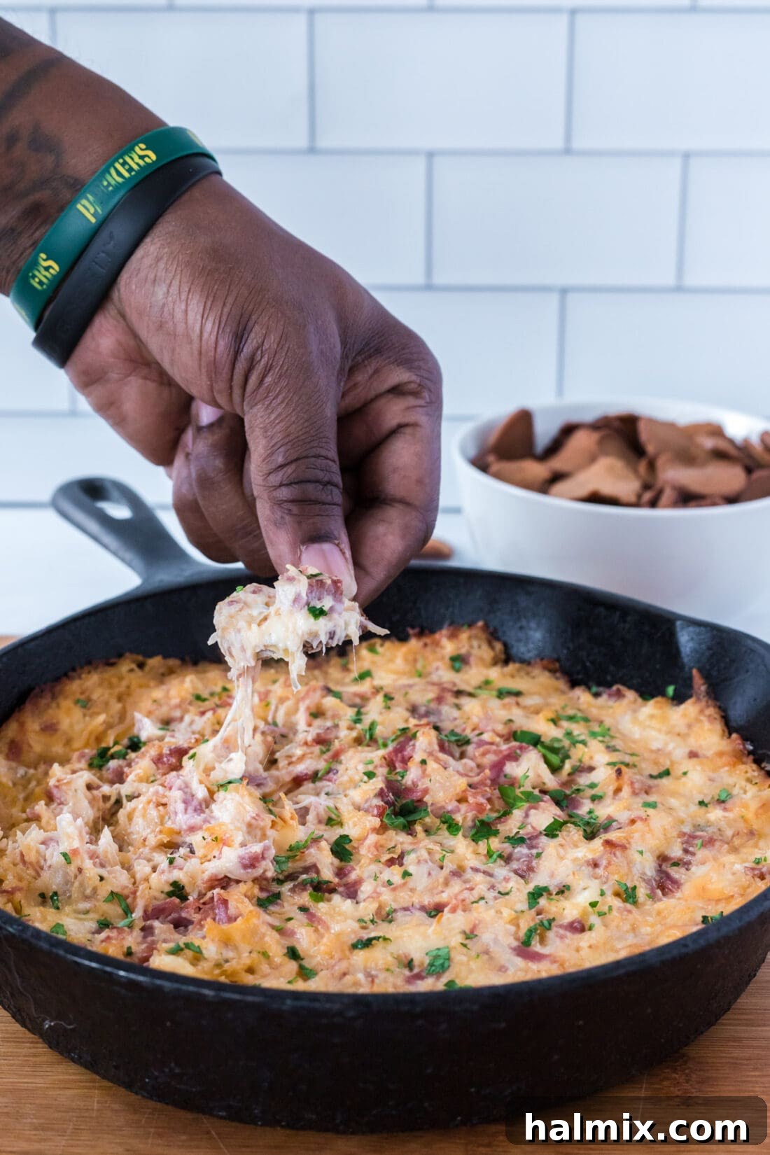 A chip being dipped into a creamy Reuben Dip, showing the rich texture and melted cheese.