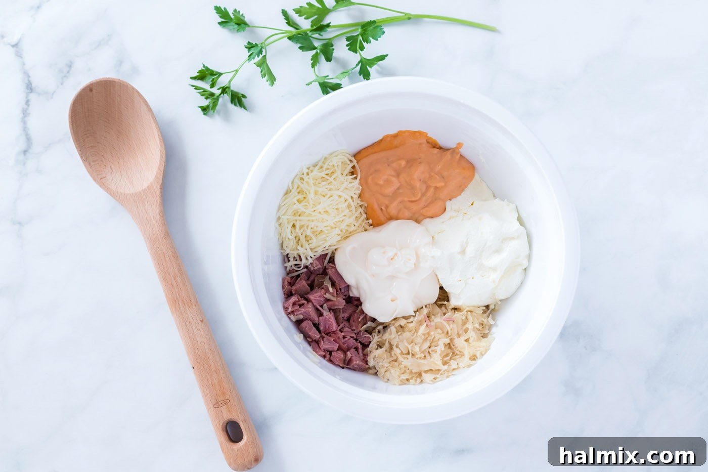 Close-up of Reuben dip ingredients in a bowl before mixing, showing chopped corned beef and shredded cheese.
