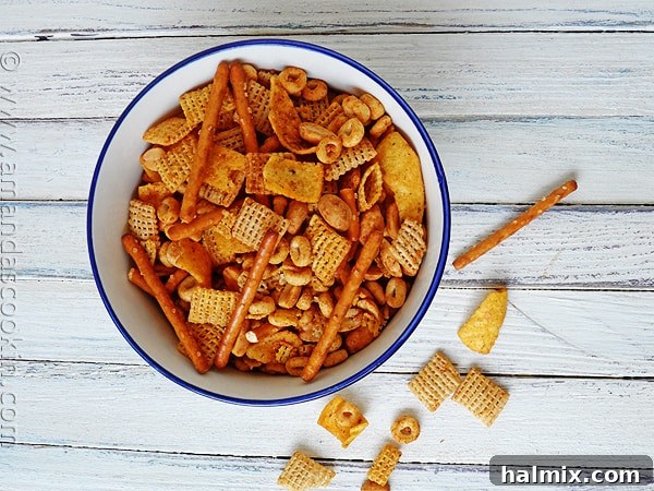 A vibrant overhead photo of a bowl brimming with golden-brown Taco Chex Mix, showcasing various cereals, Fritos, and pretzels coated in savory seasoning.