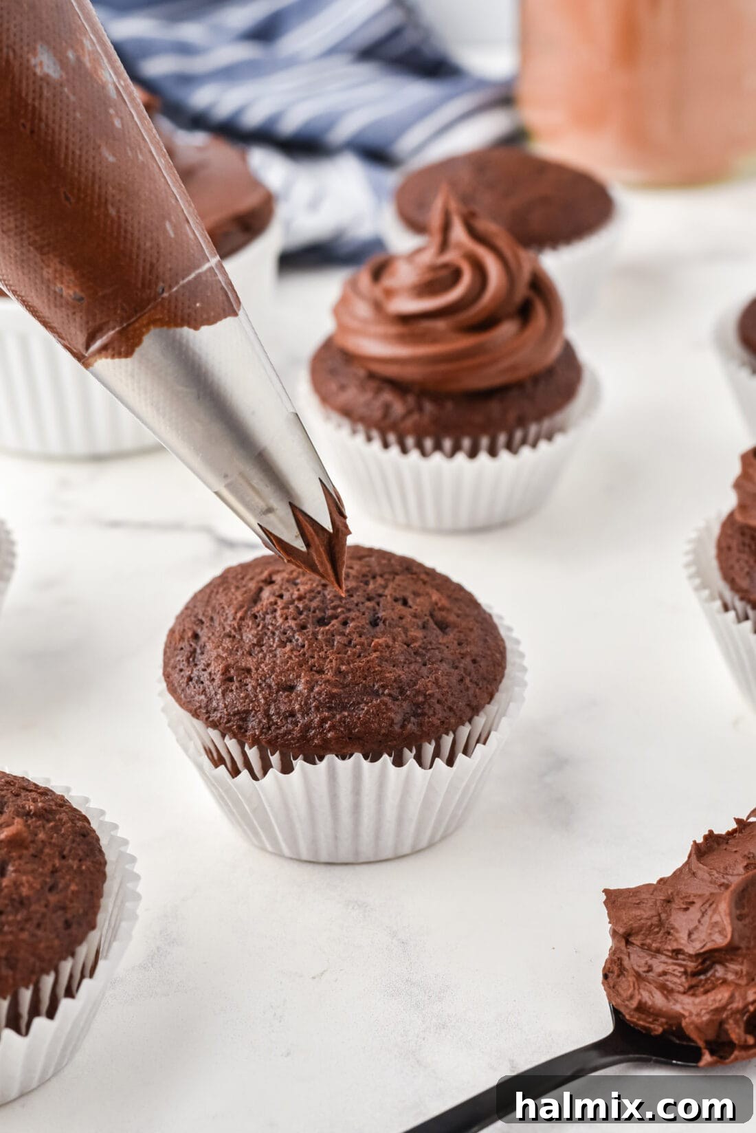 Piping Chocolate Fudge Frosting onto a cupcake