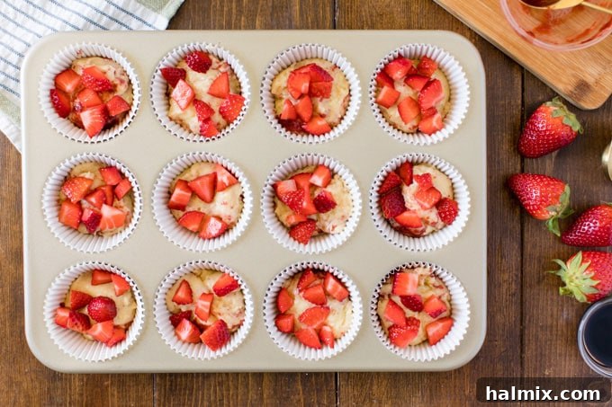 chopped strawberries on top of muffin batter in muffin tin