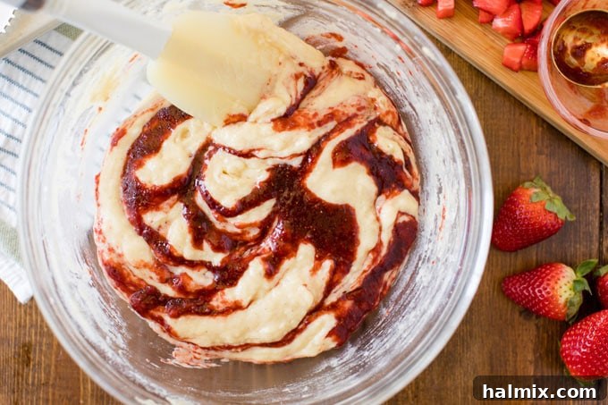 rubber spatula swirling jam into bowl of muffin batter