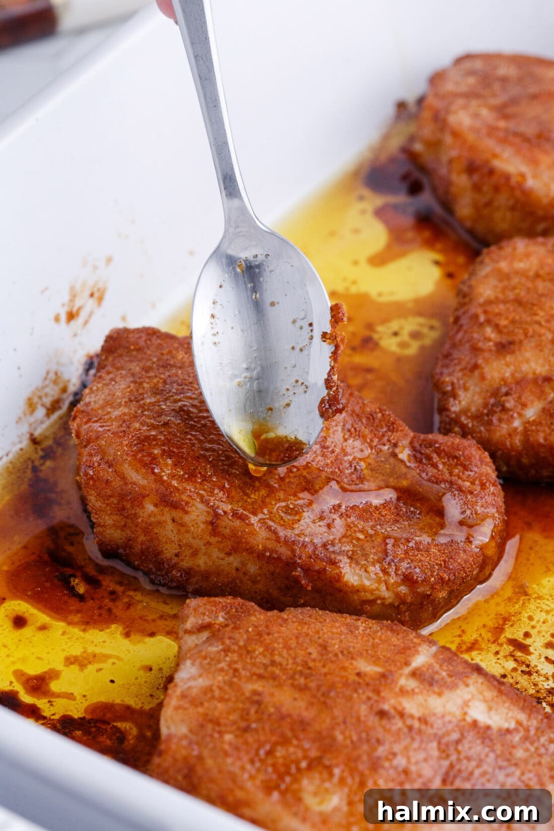 spooning juices over Baked Pork Chops