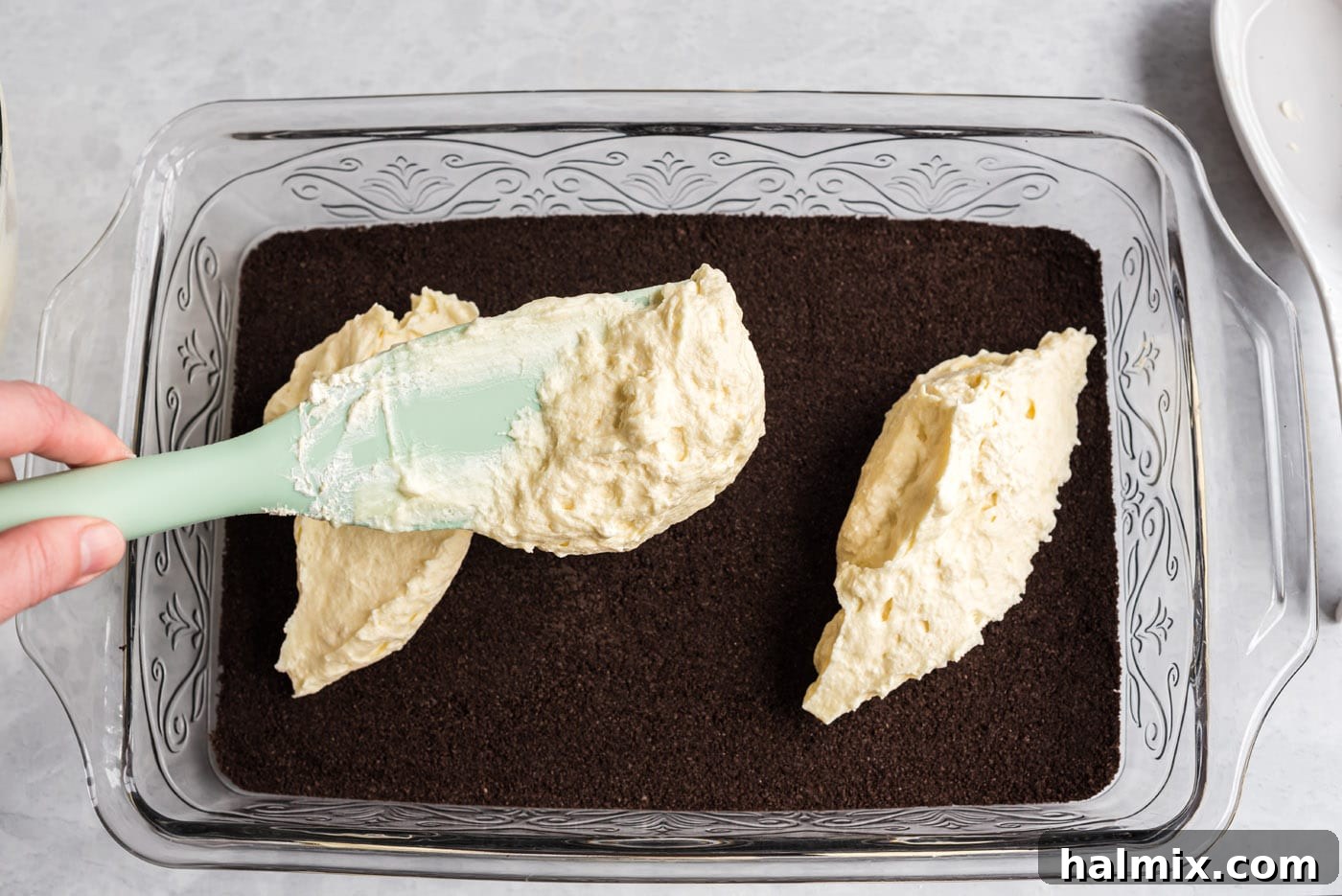 Spreading the Creamy Filling Over the Crust Spreading cream cheese mixture on top of the Oreo crust