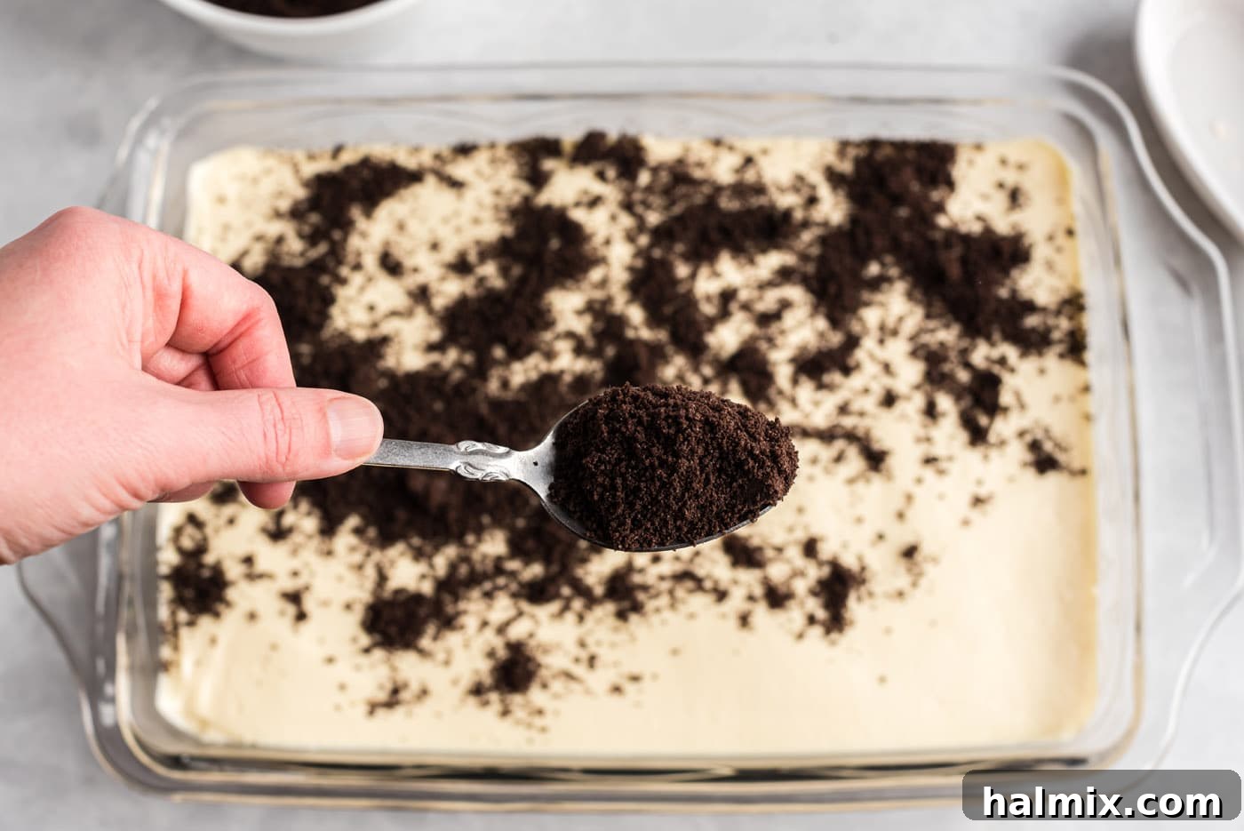 Adding the Final Layer of Oreo Crumbs Sprinkling Oreo crumbs over the dirt cake