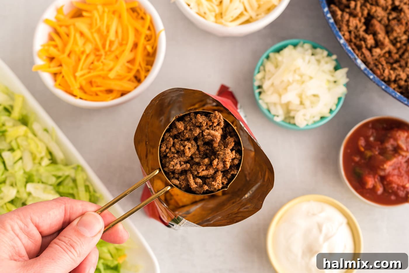 Spooning seasoned taco meat into an opened chip bag