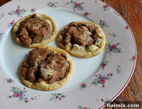 Three perfectly formed double stack chocolate chip cookies on a white plate, ready to be enjoyed.