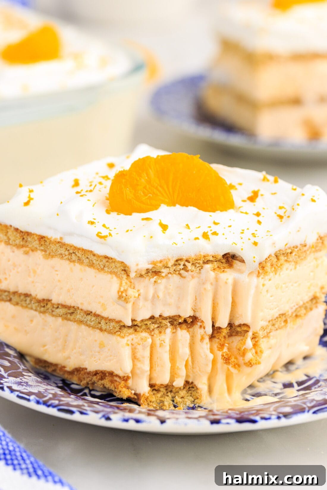 Slice of Orange Icebox Cake with a bite taken out, showcasing the layers of creamy orange pudding, graham crackers, and whipped topping