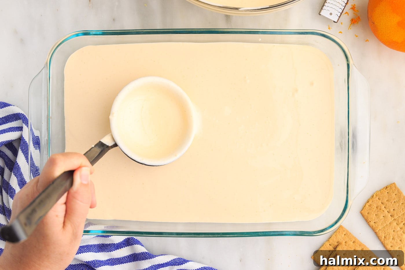 Half of the orange pudding mixture spread over the graham crackers in the baking dish