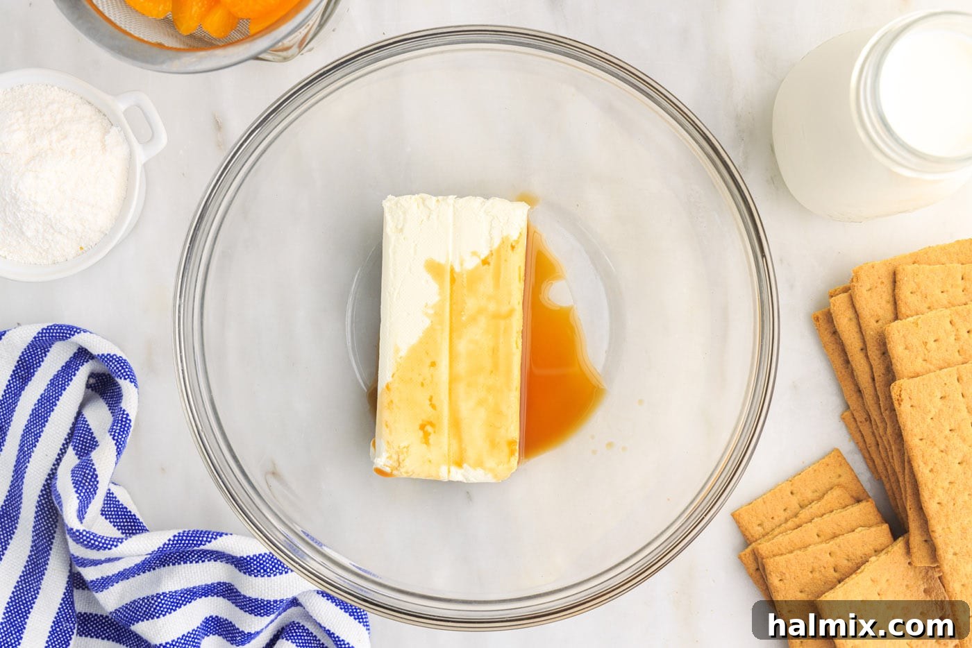 Cream cheese and vanilla extract being beaten in a mixing bowl until light and fluffy