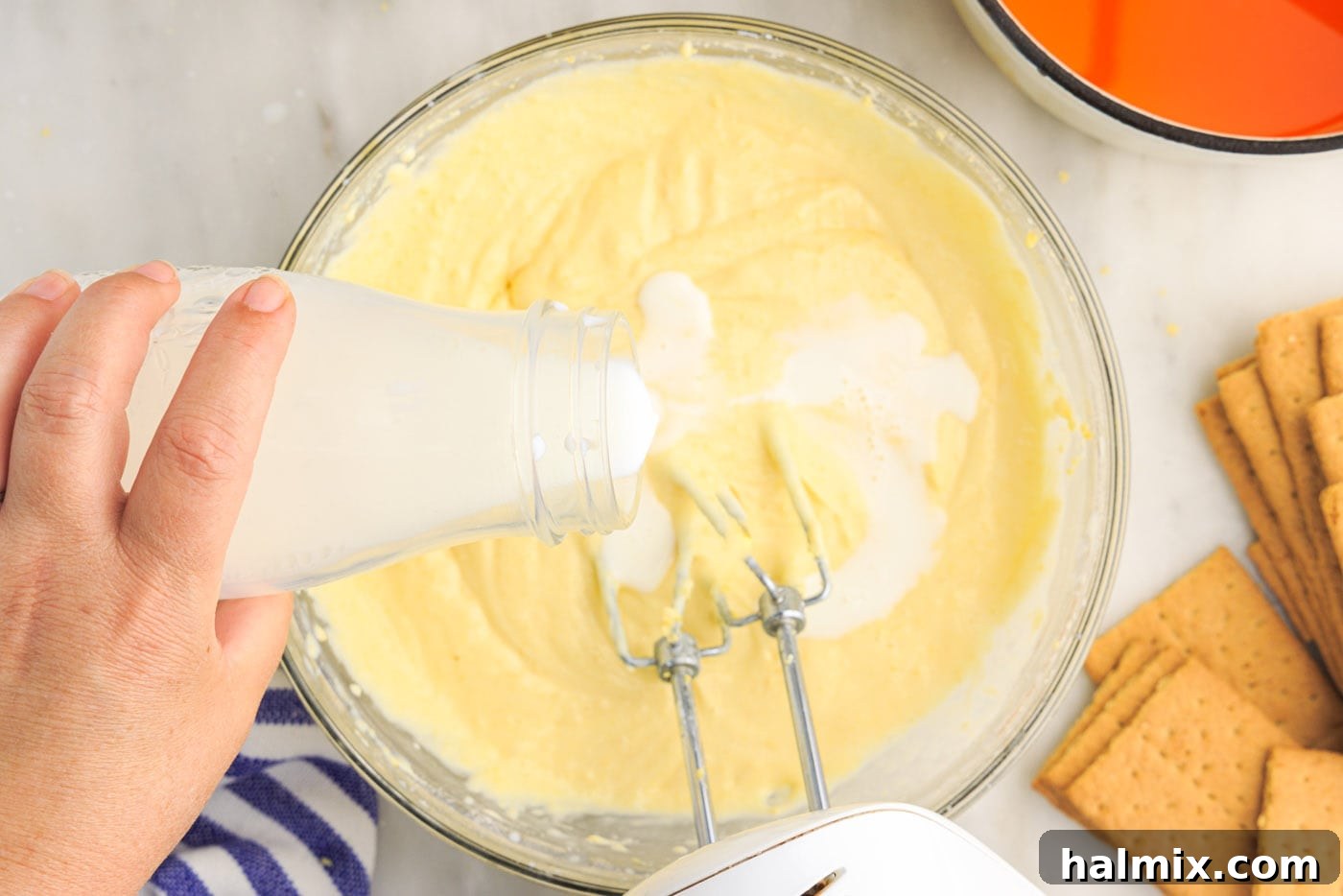 Pouring milk into the cream cheese and pudding mixture for the orange icebox cake