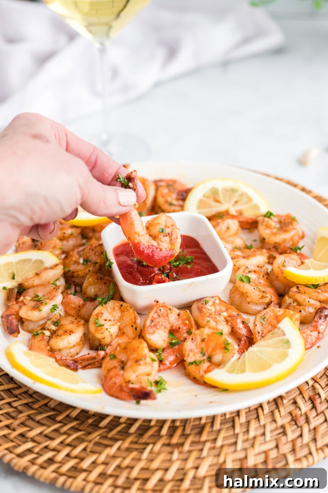 Close-up of a shrimp being dipped into cocktail sauce, highlighting its juicy texture.
