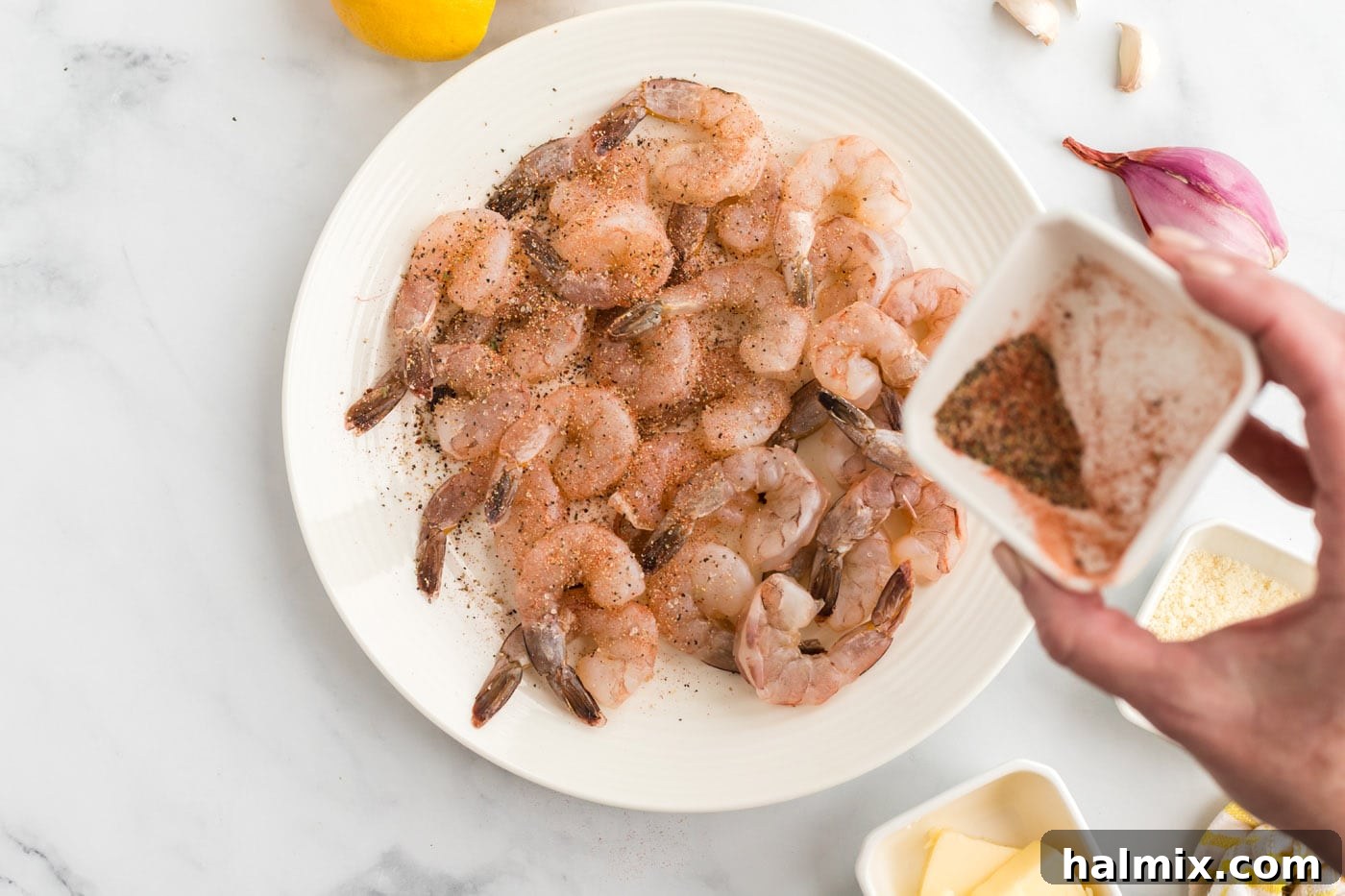 Raw shrimp being seasoned with a spice mixture in a bowl.
