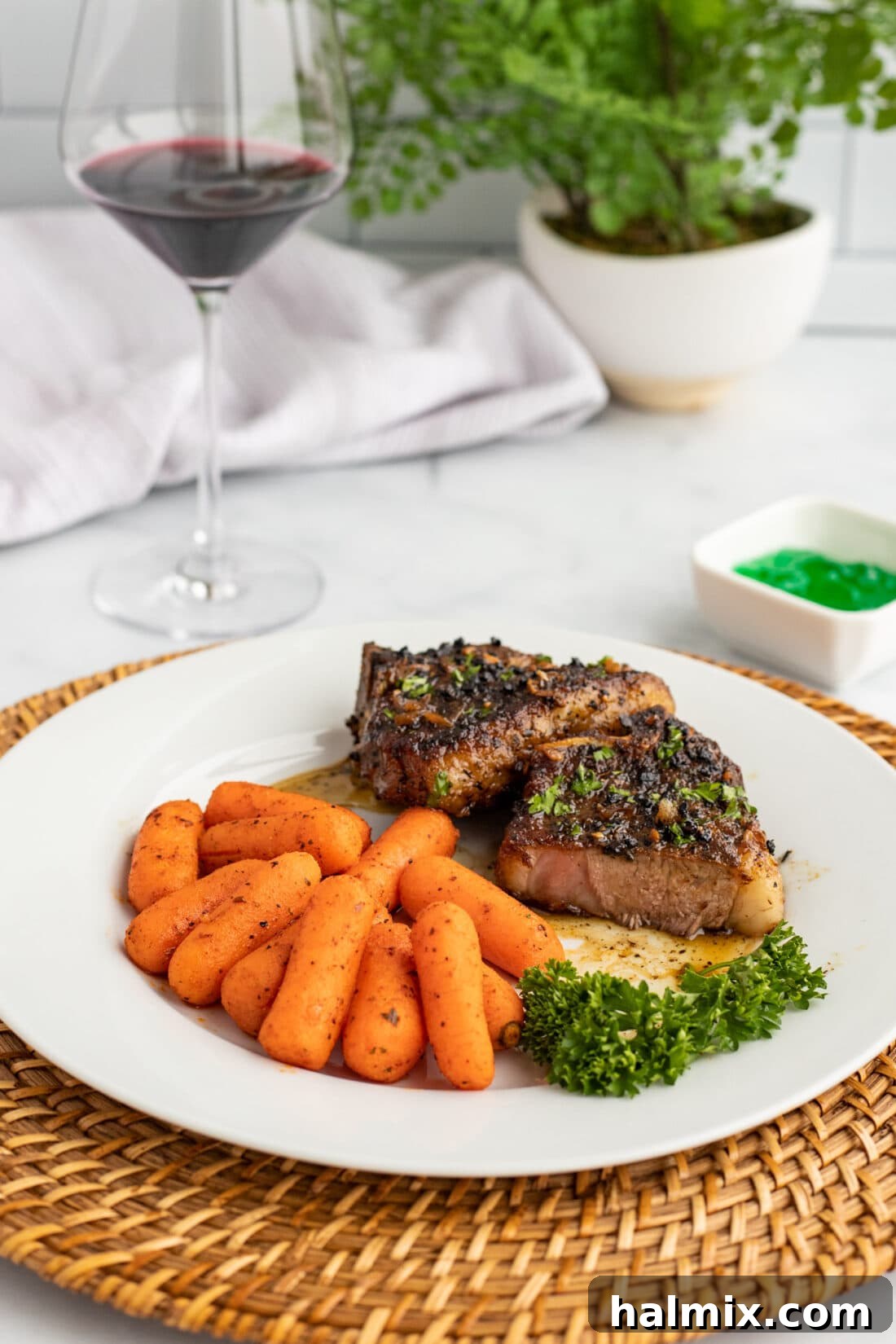 Plated lamb chops with roasted carrots and a drizzle of white wine reduction.