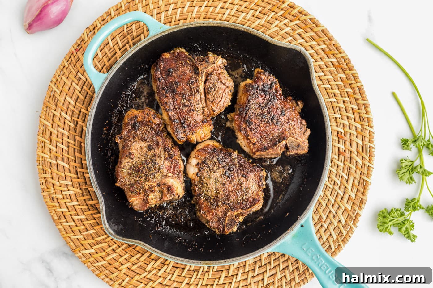 Lamb chops searing in a hot skillet, creating a perfect crust on one side.