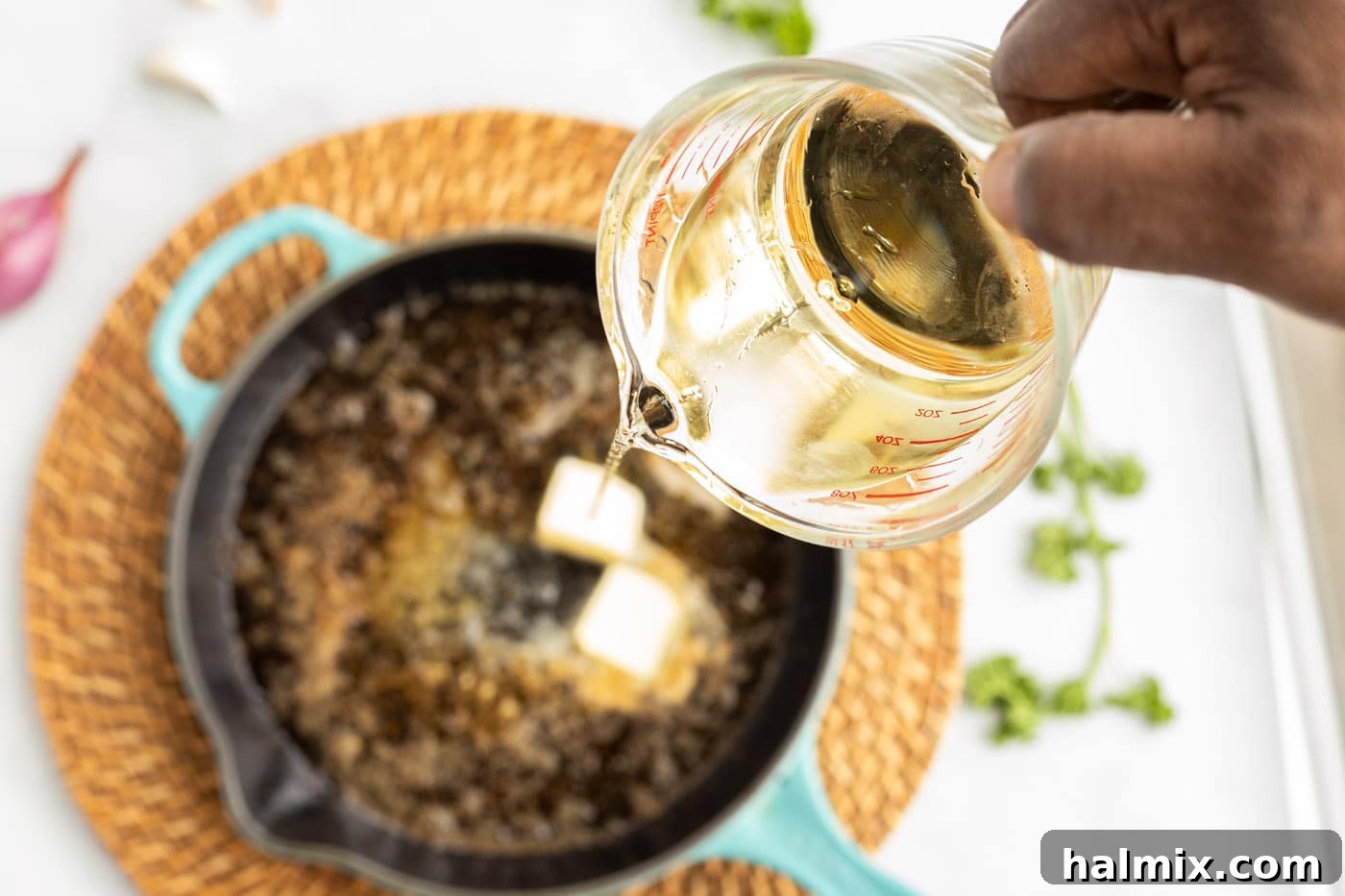 The white wine reduction simmering in the skillet with butter, garlic, and shallots, bubbling gently.