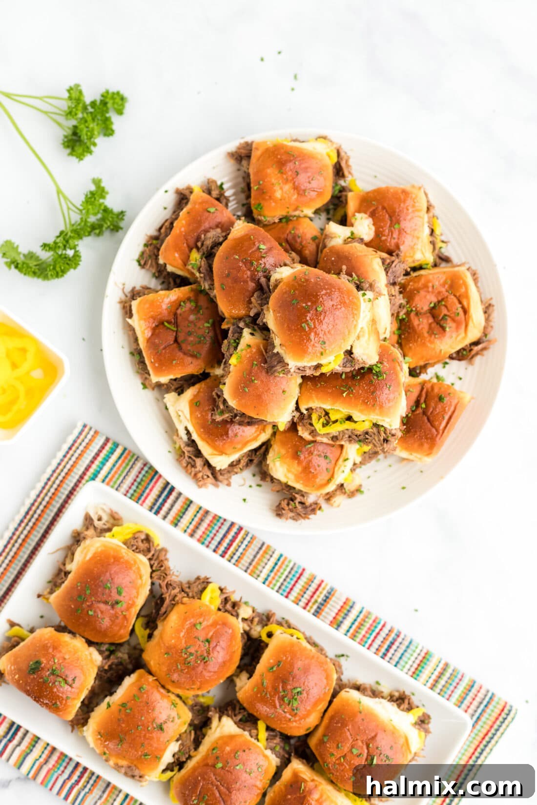 A large platter generously filled with warm, golden-brown Mississippi Pot Roast Sliders, ready for a feast.
