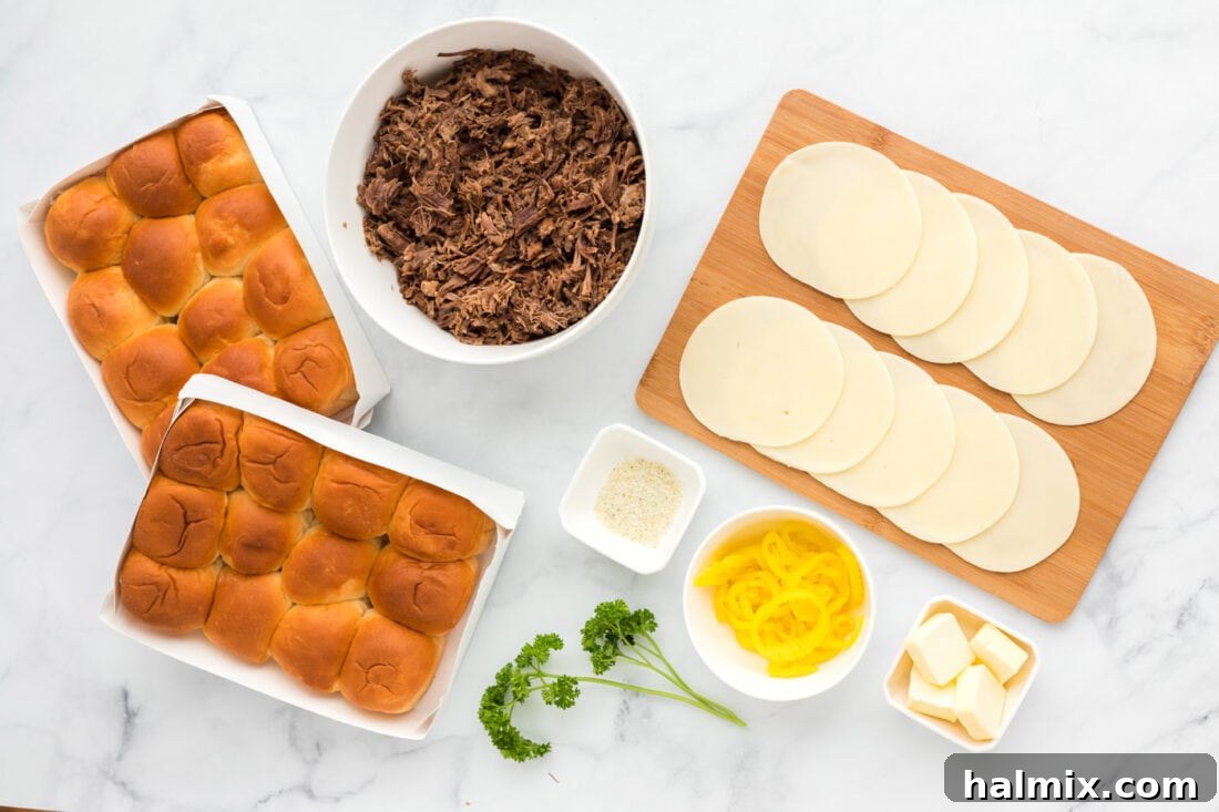 Individual ingredients for Mississippi Pot Roast Sliders laid out, including Hawaiian rolls, provolone cheese, pepperoncini, and melted butter.