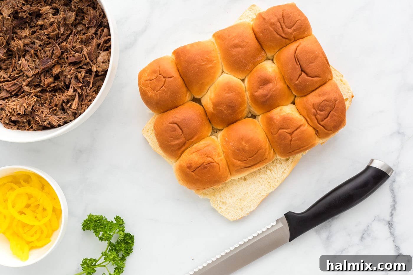 Hawaiian rolls expertly sliced in half with a bread knife, ready for assembly.