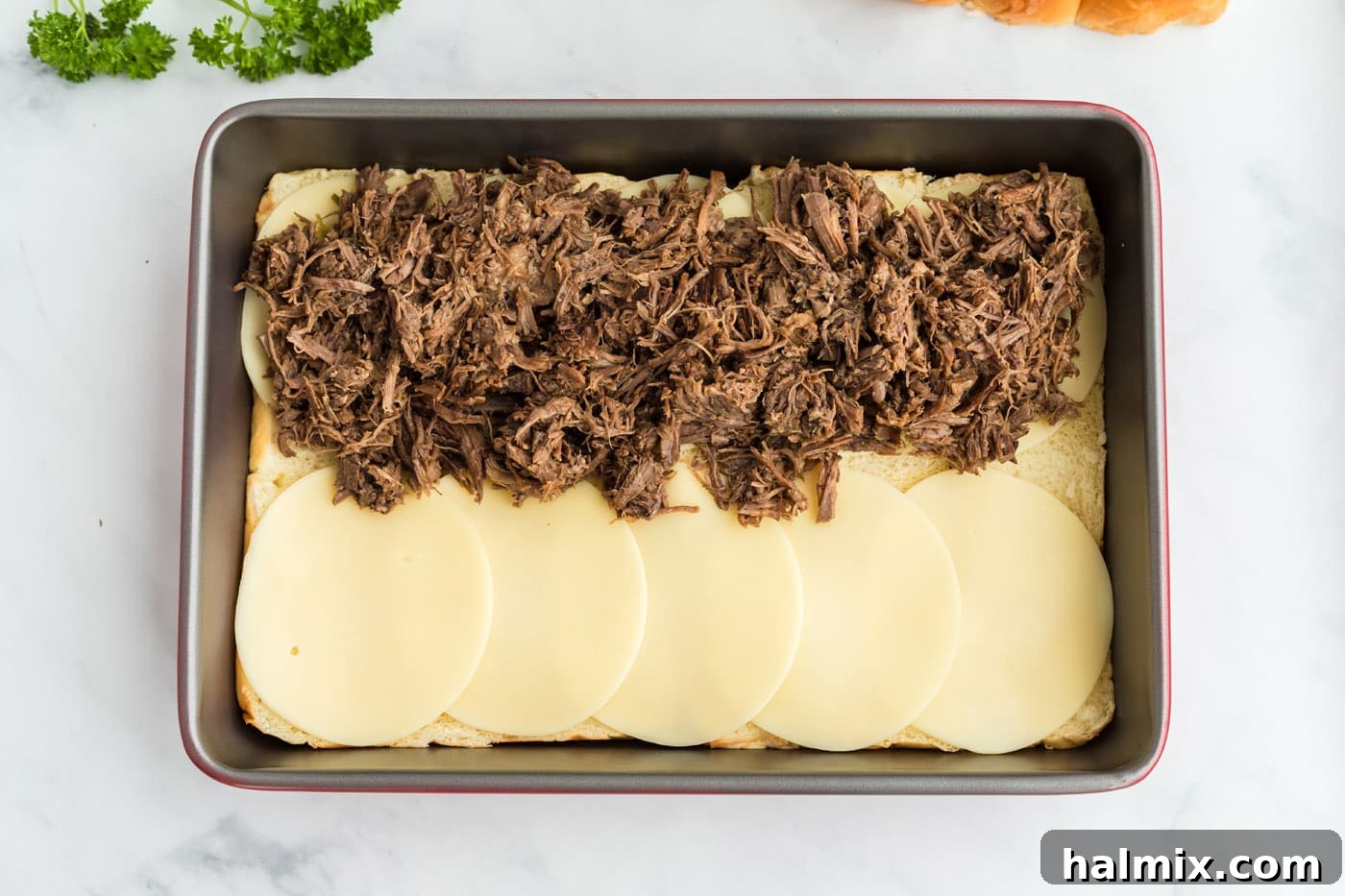Shredded Mississippi pot roast piled high on top of the provolone cheese layer and Hawaiian rolls.