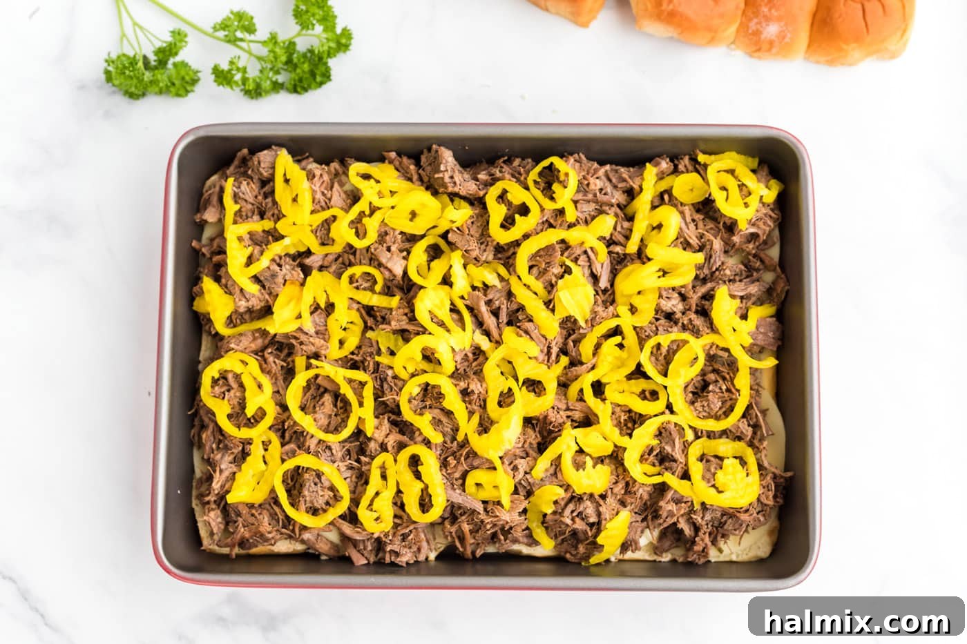 Sliced pepperoncini peppers scattered over the Mississippi pot roast in the baking pan.