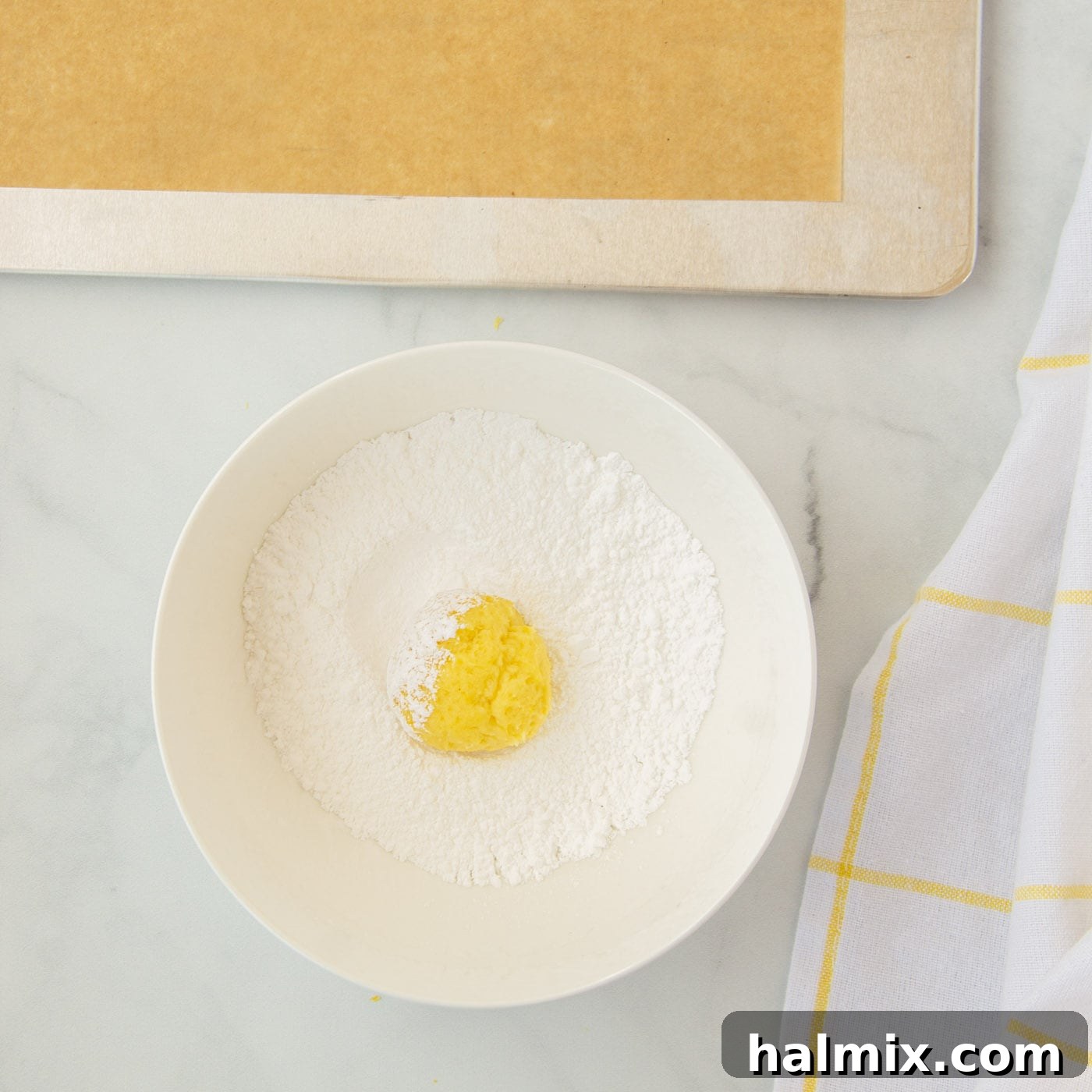 Zesty Lemon Cake Mix Cookies 11 Lemon cookie dough balls being rolled in powdered sugar to create the crinkle effect.