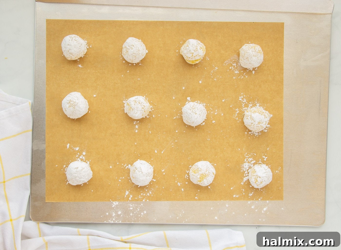 Zesty Lemon Cake Mix Cookies 12 Lemon crinkle cookies neatly arranged on a baking sheet lined with parchment paper, ready for the oven.