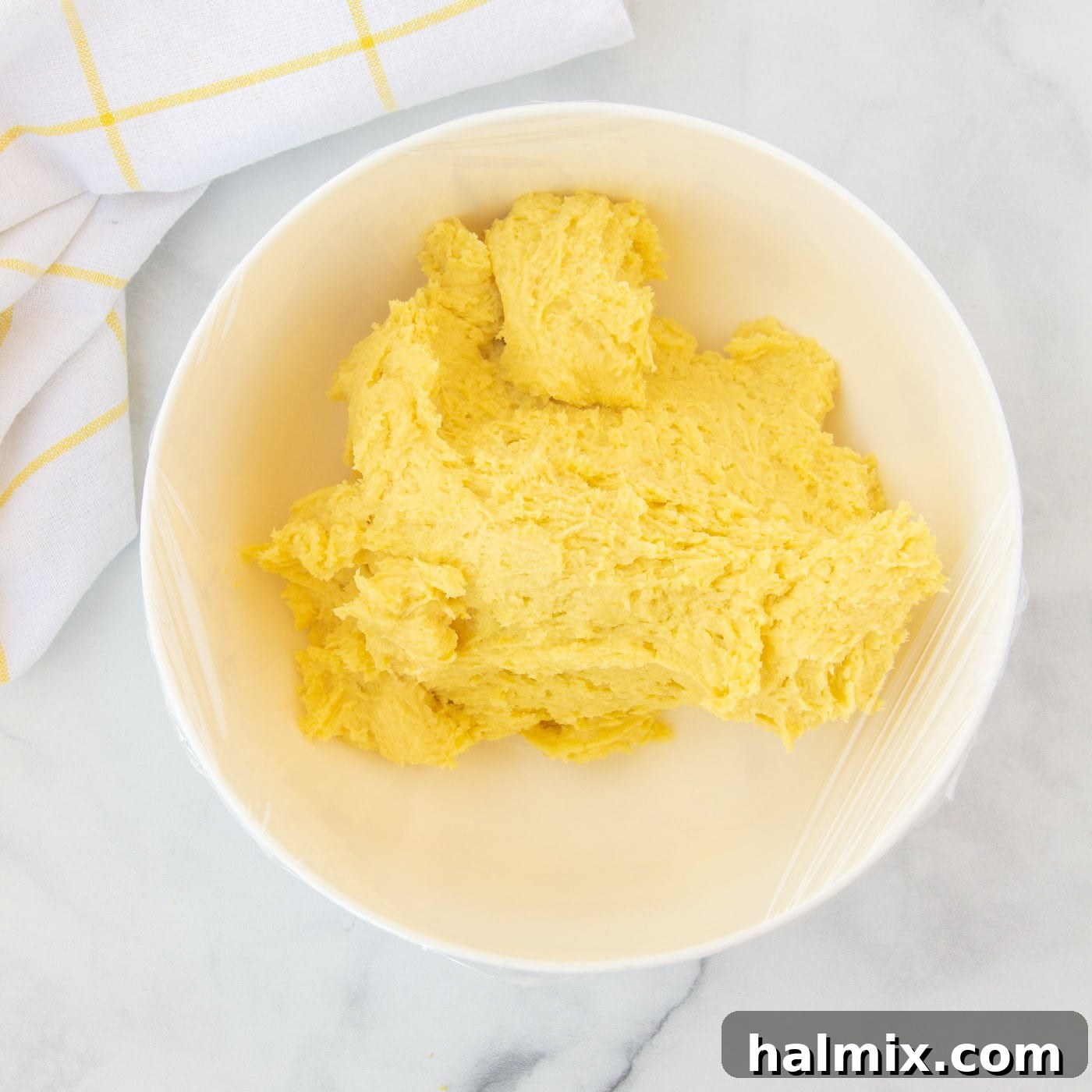 Zesty Lemon Cake Mix Cookies 10 The lemon cake mix cookie dough covered with plastic wrap, chilling in a bowl.