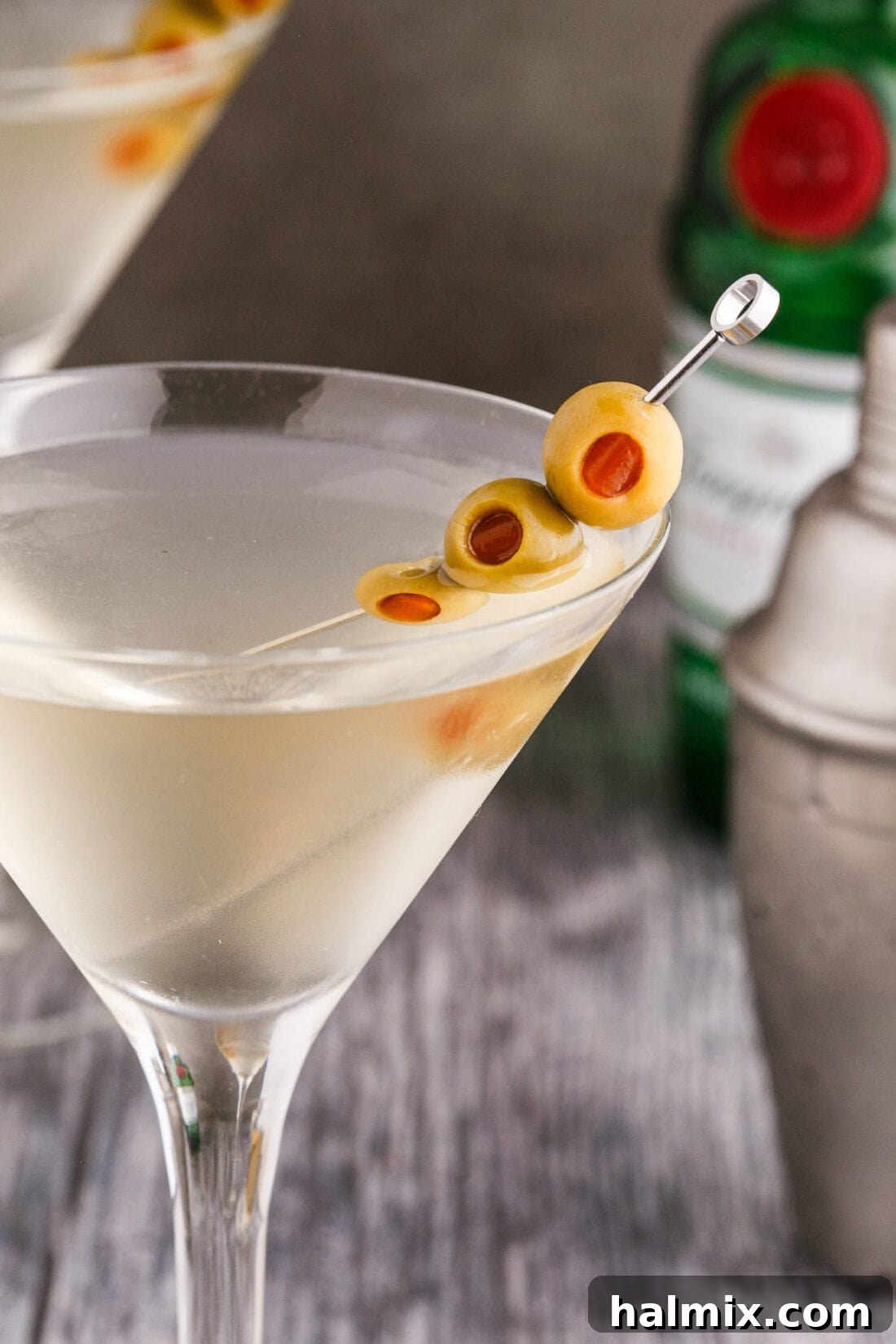 Close up shot of a Dirty Martini, showcasing its cloudy texture and olive garnish
