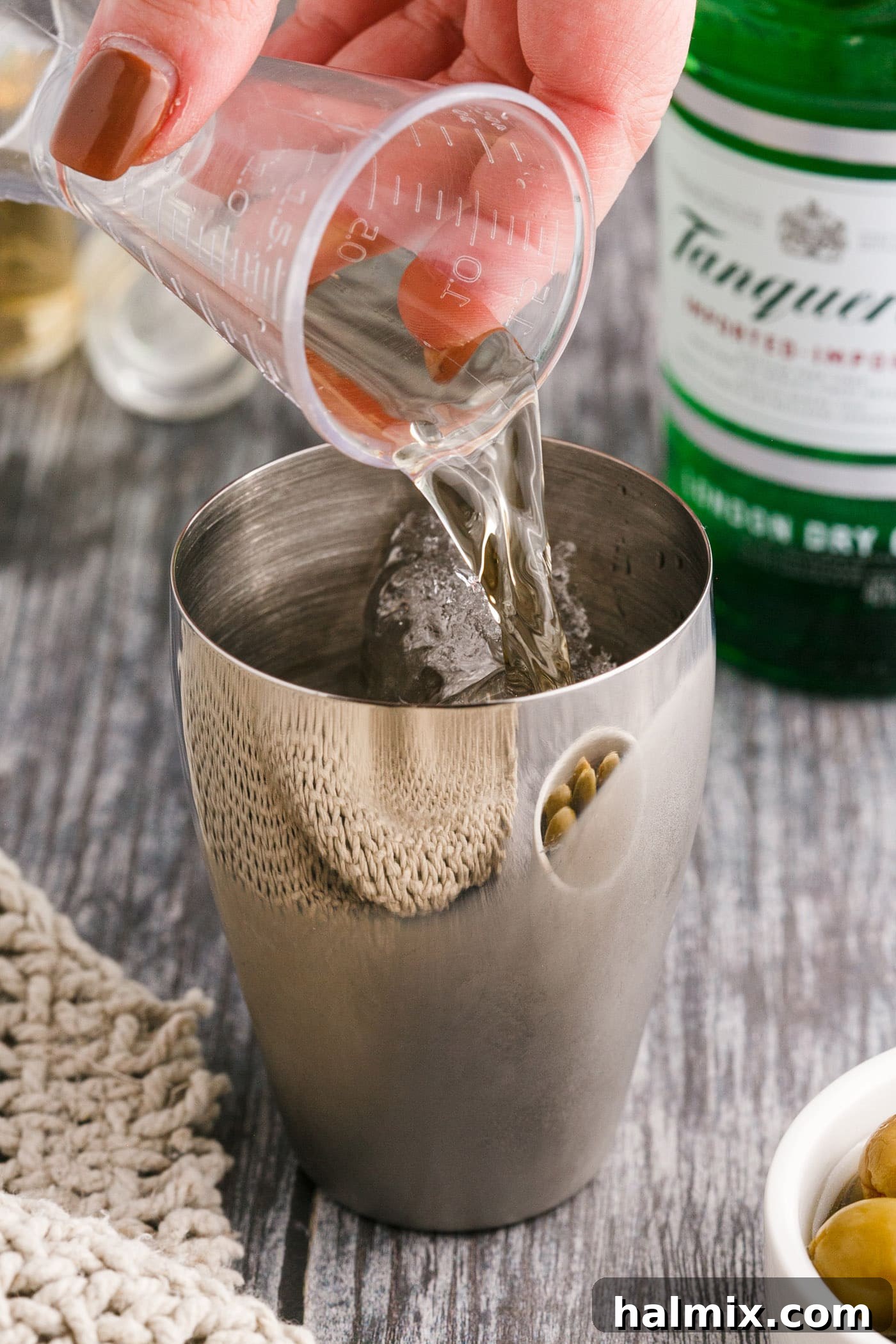 Pouring gin into a cocktail shaker filled with ice