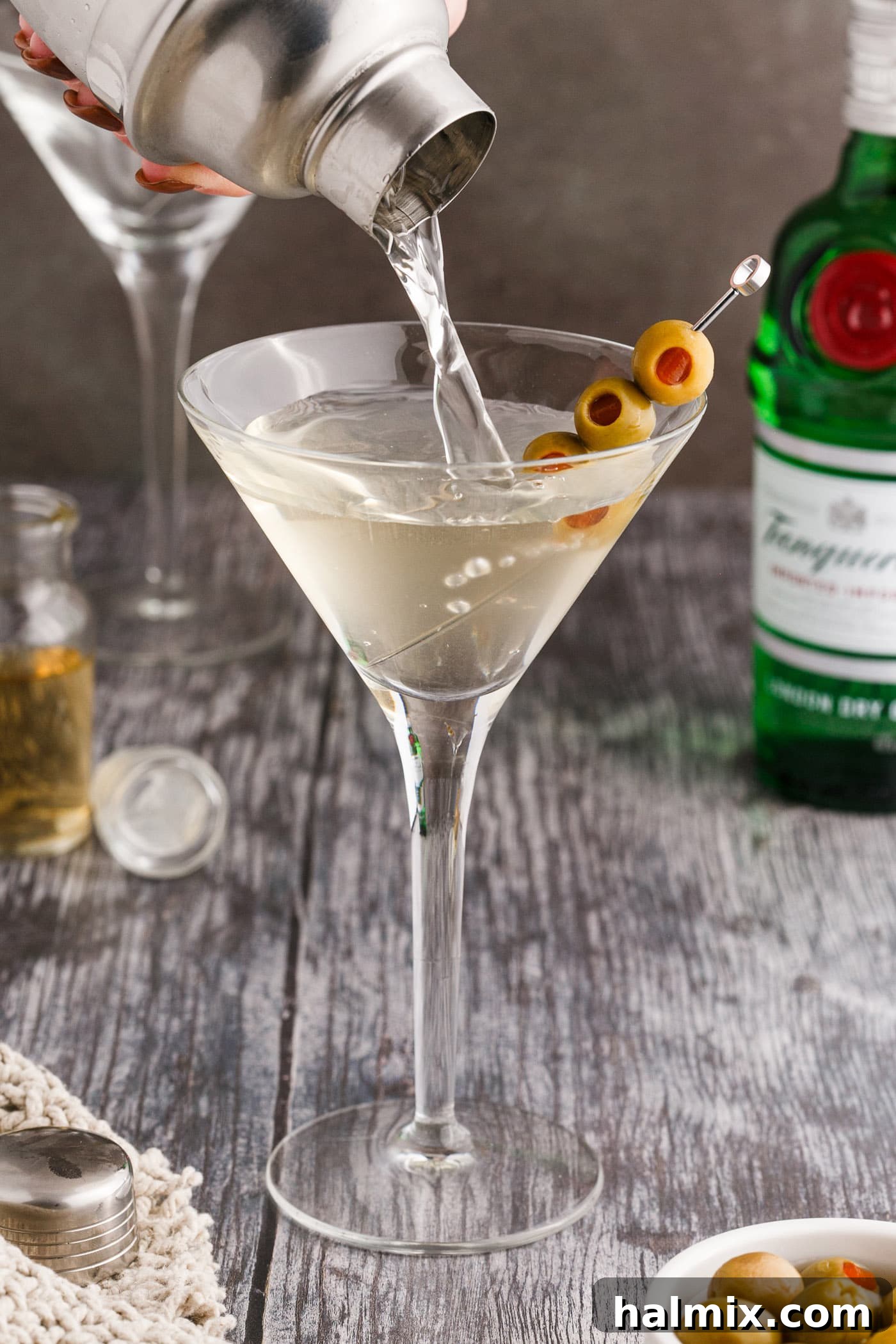 Straining a freshly shaken Dirty Martini into a martini glass