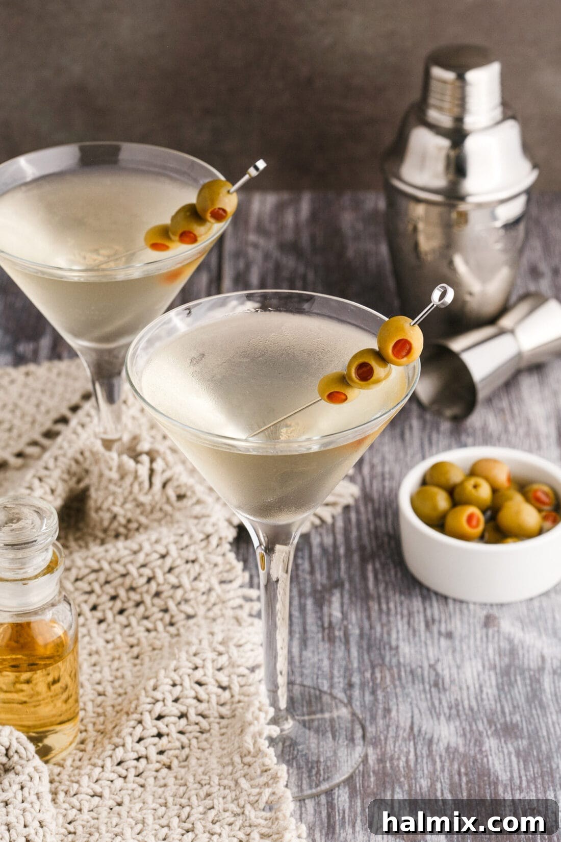 Dirty Martini served with olives and a cocktail shaker in the background