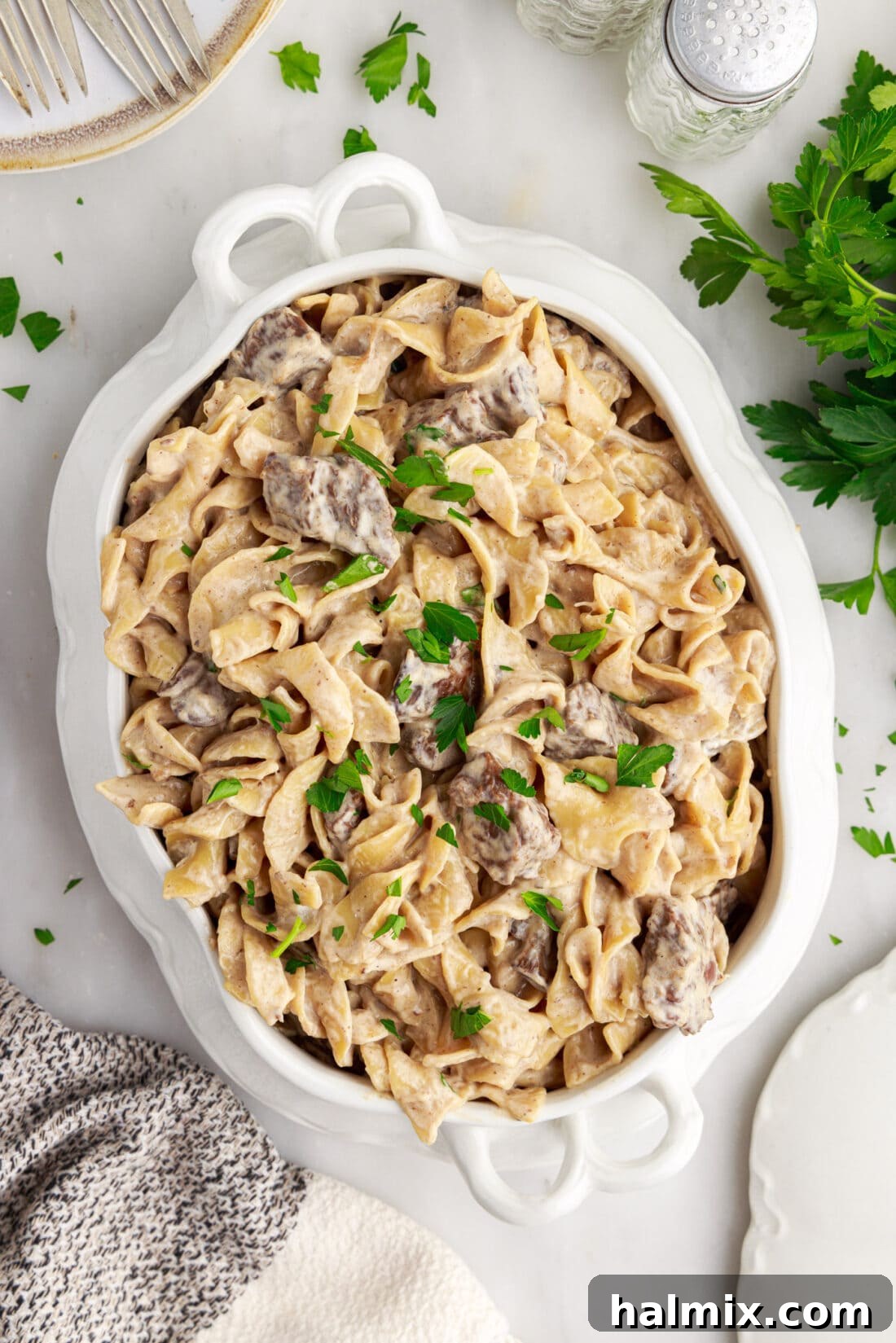 Overhead view of Instant Pot Beef Stroganoff served in a white casserole dish, garnished and ready for a family meal.