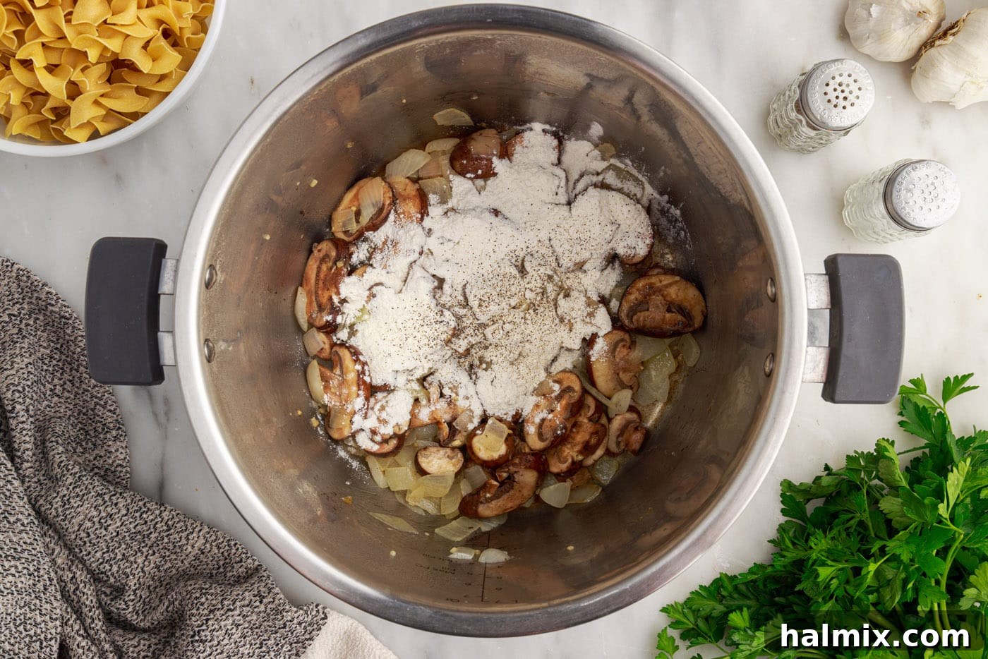 All-purpose flour sprinkled over sautéed mushrooms and onions in the Instant Pot, ready to be stirred.