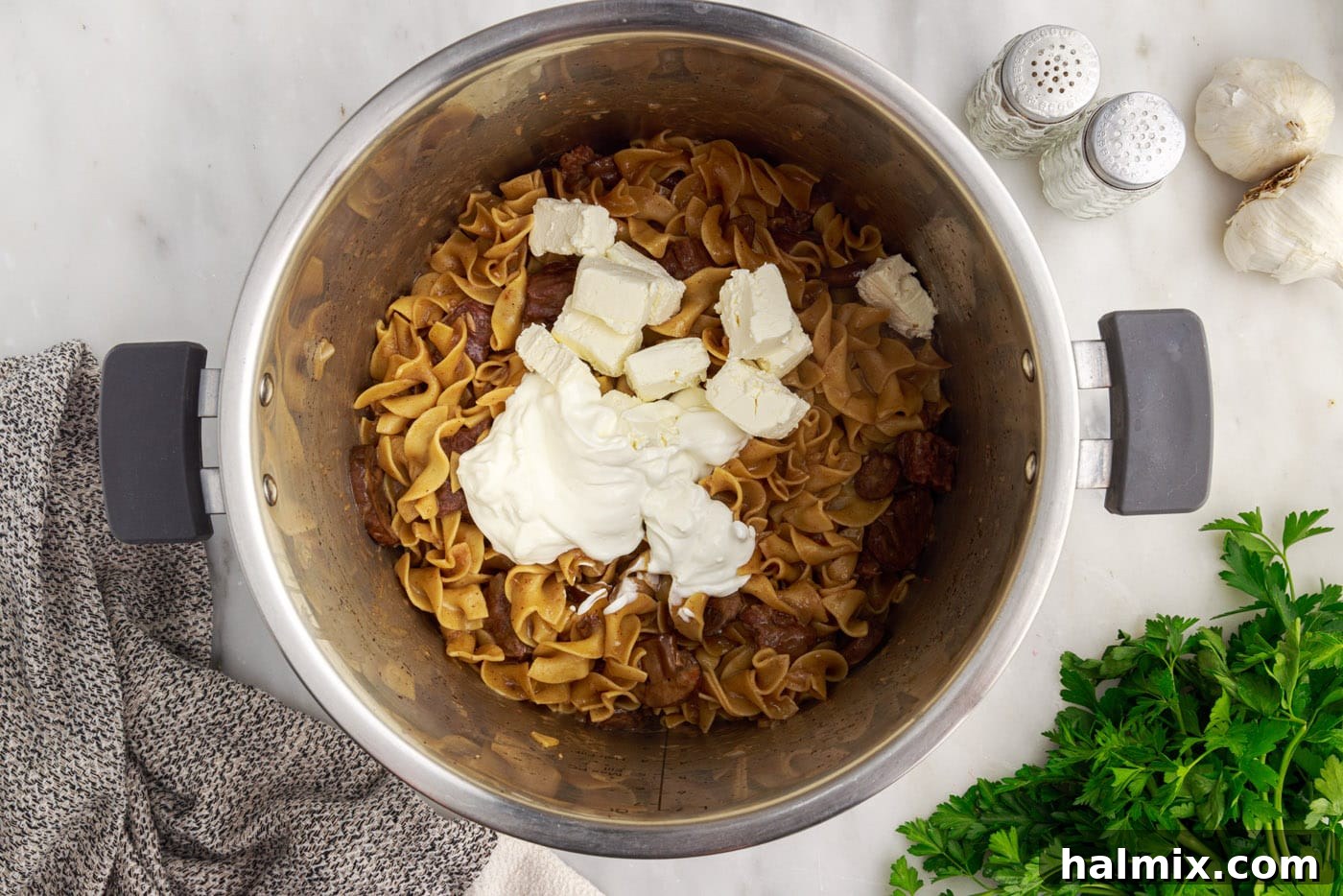 Sour cream and cream cheese being stirred into the Instant Pot Beef Stroganoff, creating a rich and creamy sauce.